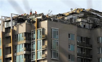 　　昨日，身穿橘黃色馬甲的工作人員在人濟(jì)山莊樓頂拆除違章建筑。新京報(bào)記者 吳江 攝