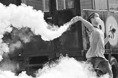 12月2日，泰國(guó)曼谷，一名反政府示威者在總理府附近向負(fù)責(zé)執(zhí)勤的警察投擲催淚彈。英拉請(qǐng)求示威者不要再試圖占領(lǐng)政府工作部門(mén)，不要逼迫政府工作人員選邊站。