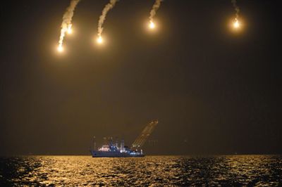 22日，搜救人員在照明彈的光亮下連夜搜救。