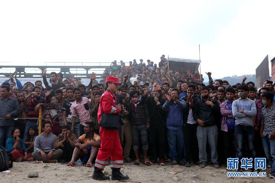 圍觀的尼泊爾民眾在中國國際救援隊(duì)成功搜救出幸存者后向搜救隊(duì)員歡呼致意。