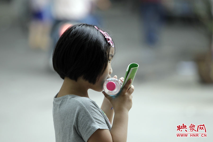 6月7日，鄭州回中考點，一名孩子拿著一瓶礦泉水，等待哥哥走出考場