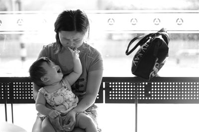 昨日，肯德基京廣中心店門口，姜女士提起跟養(yǎng)父母的關(guān)系時(shí)落淚，懷中9個(gè)月的女兒笑著跟她玩。新京報(bào)記者 薛珺 攝