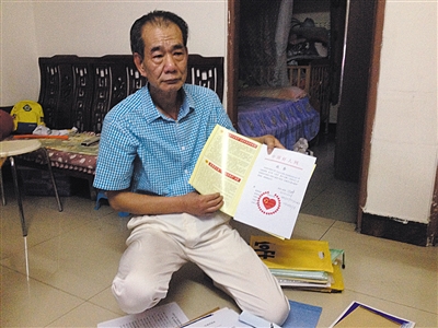 翻出一家網(wǎng)站贈(zèng)予的“中國好人”證書，區(qū)少坤單膝跪在地上，“你看，我是中國好人啊?！?范春旭 攝