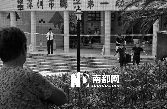 →7月19日，鵬興花園第一幼兒園門前，民警在現(xiàn)場進行完勘查取證后，園長和保安的尸體被運走。南都記者 徐文閣 攝