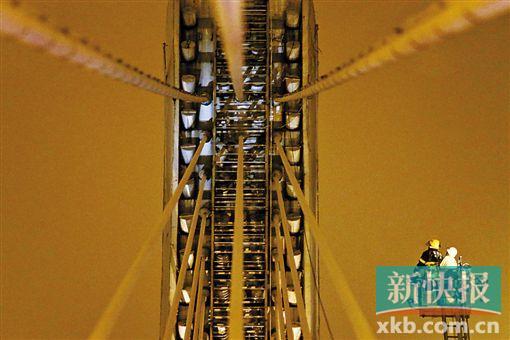 截至今日零時，男子仍未有下橋舉動。圖為公安和消防人員乘消防云梯在高空上和男子交談。