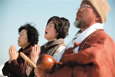 23日，一名僧侶引領人們?yōu)樗勒咂矶\。