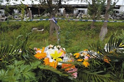 昨日，吉林省德惠市吉林寶源豐禽業(yè)有限公司燃燒事故現(xiàn)場警戒線外，遇難者家屬在路邊擺放了花圈祭奠逝去的親人。吳江 攝