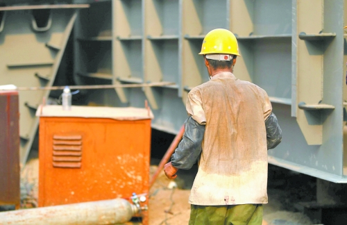 工地上，一建筑工人的衣服被汗水浸透。