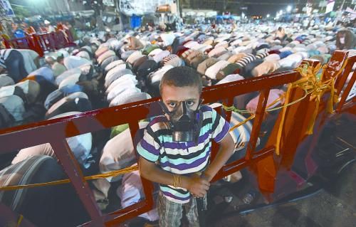 當(dāng)?shù)貢r(shí)間28日晚，在埃及開(kāi)羅納賽爾城，一名小男孩頭戴防毒面具參加穆兄會(huì)的集會(huì)示威。