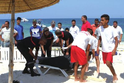 6月26日，在突尼斯蘇塞，救生員和醫(yī)務人員在發(fā)生襲擊事件的海灘運送一名死者的遺體。新華社發(fā)