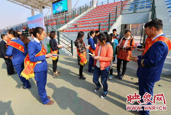 活動現(xiàn)場工作人員給同學(xué)們發(fā)放宣傳冊、環(huán)保袋。