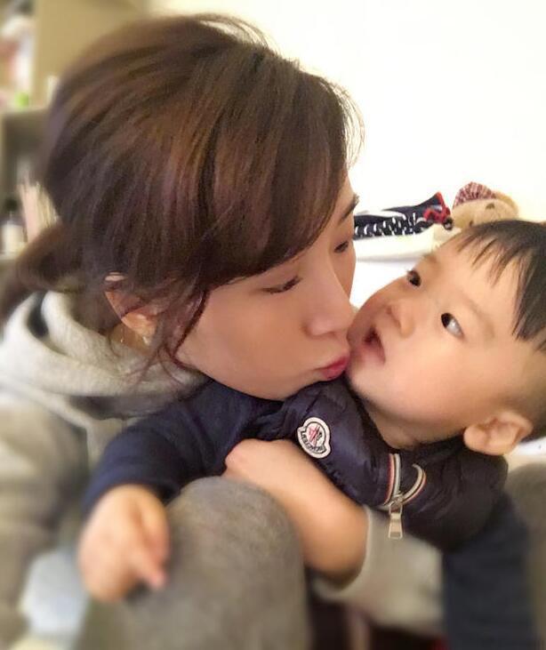 照片中李念狂吻兒子，小寶貝自顧自地玩著。