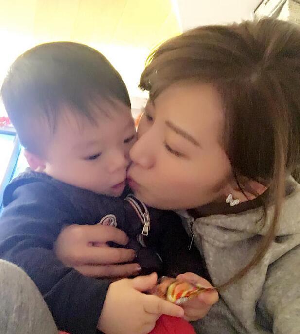 照片中李念狂吻兒子，小寶貝自顧自地玩著。