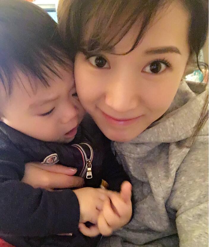 照片中李念狂吻兒子，小寶貝自顧自地玩著。