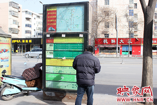 一名男子在貼滿(mǎn)小廣告的公交站牌前駐足