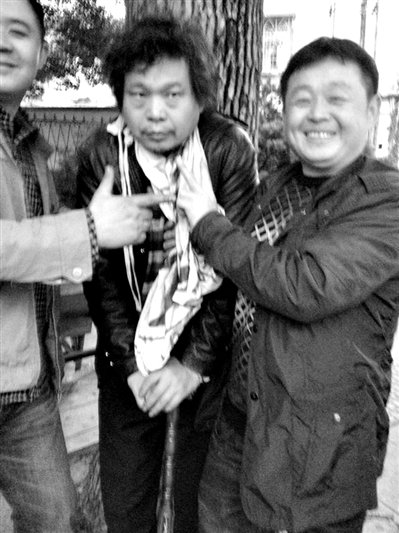 兩名接訪人員與患有癌癥的訪民段新德合影時，面帶笑容擺出勝利的手勢。