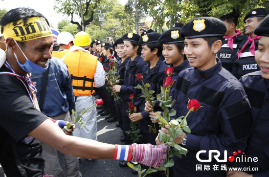 2013年12月03日,曼谷總理府與曼谷警署允許反政府示威民眾進(jìn)入,雙方進(jìn)入暫時(shí)“停戰(zhàn)”狀態(tài)迎接泰王生日。曼谷警察總署,女警們手持鮮花送給反政府示威民眾。圖片來源:Manish Swarup/東方IC