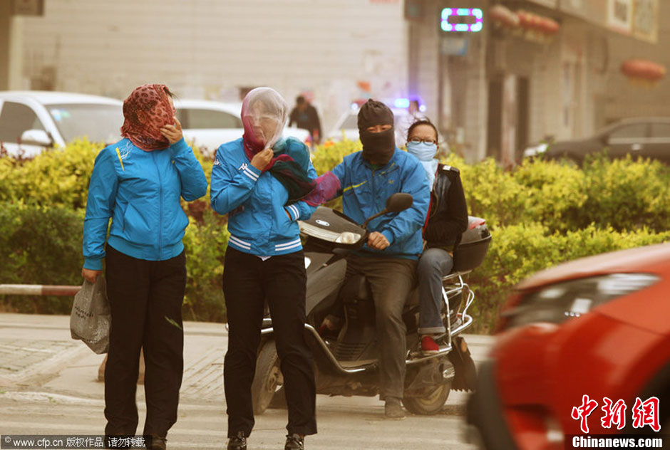 2014年04月23日，新疆維吾爾自治區(qū)吐魯番地區(qū)，市民戴著口罩行走在大風(fēng)沙塵中的吐魯番市街頭。