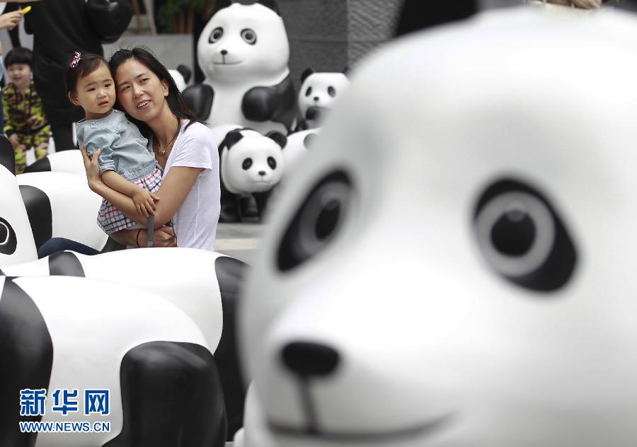 6月2日，一位家長帶著孩子在上海街頭和大熊貓模型合影。
