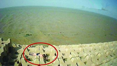 孫正龍游上岸，趴在海邊精疲力盡。