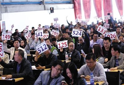 競(jìng)拍者正在練習(xí)舉牌動(dòng)作，以便拍賣時(shí)讓工作人員看清號(hào)牌。