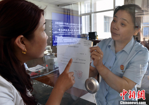 資料圖：2015年5月4日，河北石家莊市橋西區(qū)人民法院立案庭庭長齊燕正在為立案人辦理相關(guān)手續(xù)，完成整個過程只用了5分鐘。當(dāng)日是立案登記制改革首個工作日，該院共立案36件，立案率達(dá)到90%。中新社發(fā) 翟羽佳 攝