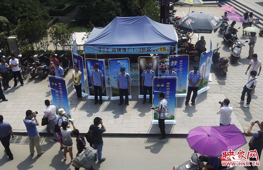 執(zhí)法人員用宣傳牌圍擋占道經(jīng)營(yíng)攤位。