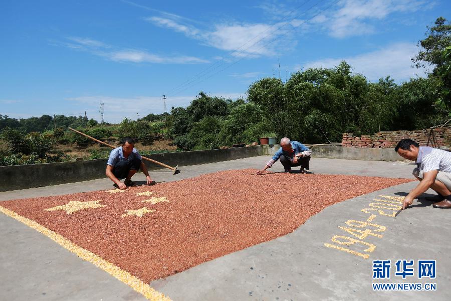 村民馬玉明（左一）用豐收的高粱和玉米在院壩里擺國(guó)旗為祖國(guó)慶生。