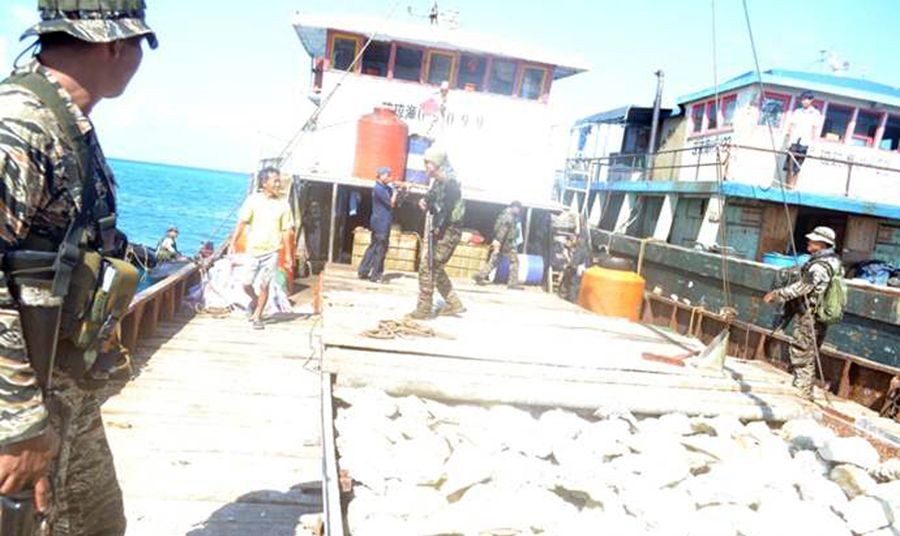 圖為菲律賓海軍持槍檢查中國(guó)漁民的照片。