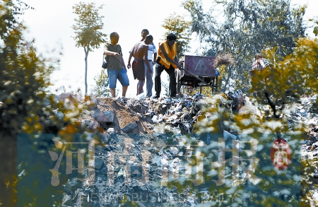 有人正在傾倒建筑垃圾，不遠(yuǎn)處就是村民的水井